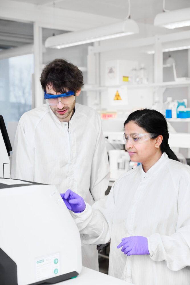 Two NorthX Biologics employees, a man and a woman, working in the lab beside a bioprocessing instrument.